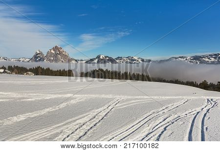 View in the village of Stoos in Switzerland in winter summits of the Alps rising from sea of fog.