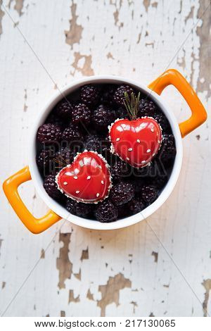 A full blackboy plate with a dessert in the form of a heart stands on a wooden background, close-up.