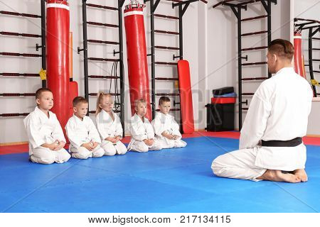 Male karate instructor with little children in dojo