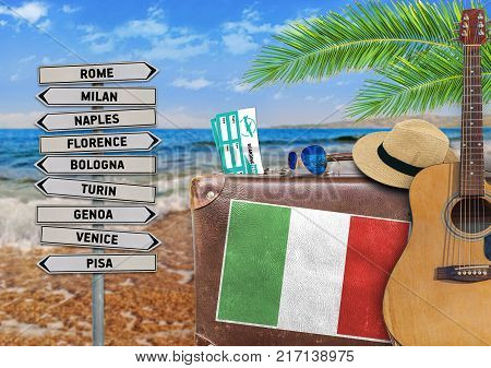 Concept of summer traveling with old suitcase and Italy town sign