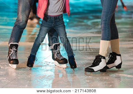 cropped shot of young family in skates skating together on rink