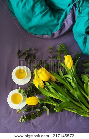 Yellow tulips and two cups of tea in bed, morning