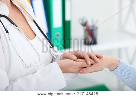 Hand of doctor reassuring her female patient. Medical ethics and trust concept