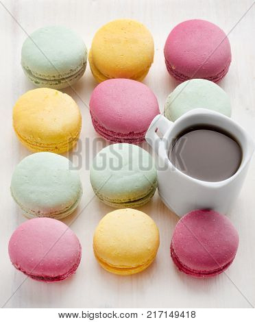 Dessert macaroons with a cup of black coffee. Multicolored cakes. Tasty breakfast.