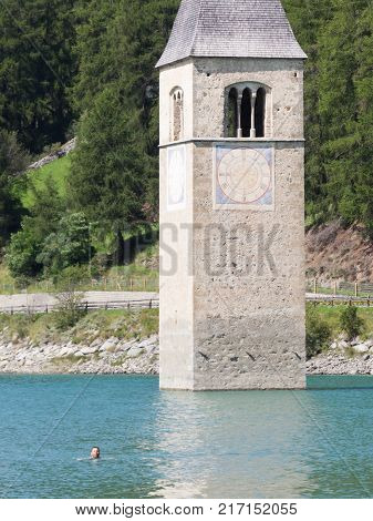 Submerged Tower Of Reschensee Church, Man Swimming Next To It