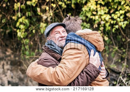 Senior father and his young son on a walk in town, hugging.
