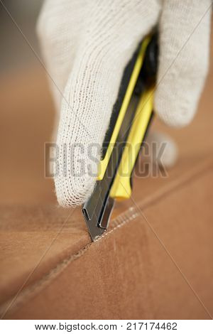 Opening box with paper knife close-up. Hand in glove with knife unpacking