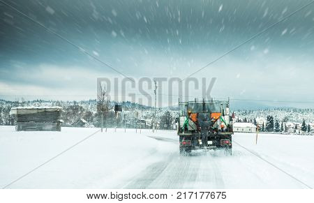 Winter Service Truck Or Gritter Spreading Salt On The Road Surface To Prevent Icing In Stormy Snow W