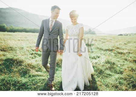 Beautiful wedding couple, love on the sunset. Fielf with view on mountains.