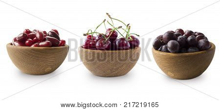 Dark red berries on a white background. Cornels cherries and grapes in a wooden bowl. Berry with copy space for text. Ripe and tasty berries isolated on white.