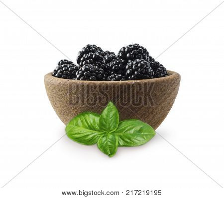Blackberries in a wooden bowl with copy space for text. Ripe and tasty black berry isolated on white. Blackberries with basil on a white background.