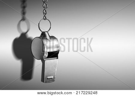 Hanging silver metal whistle close up photo.