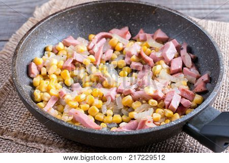 Filling for a pie in a frying pan. Bacon onion and corn