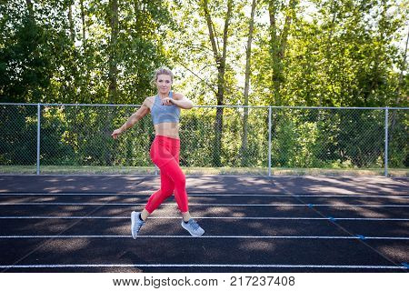 Grapevine exercise shown to the camera by a young female athlete while working out on an outdoor track in the summer.