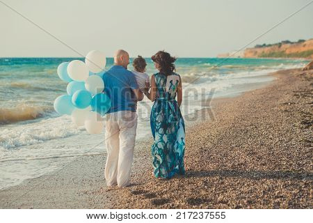 Family Together Enjoying Summer Vacation Time On Sandy Beach On Amazing Scene Of Sea Cliff And Sky W