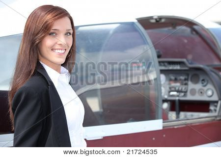 Feminino-piloto em pé ao lado do cockpit de um avião leve