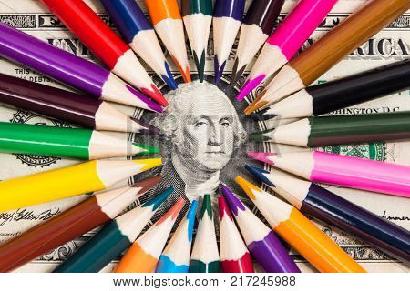 A portrait of Washington on a one-dollar, surrounded by colored pencils in the center of the frame close-up.