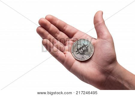 The boy holds a silver bitcoin in the palm of his hand. Isolated