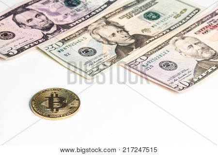 New banknotes of US dollars and a gold coin of crypto currency on a white background.