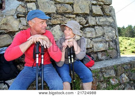 Portrait of happy senior hikers resting by stone house