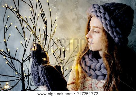 Winter fashion accessories.Young woman dressed for cold weather in grey snood hat and mittens admiring christmas lights.