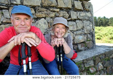 Portrait of happy senior hikers resting by stone house
