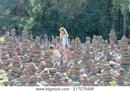 GETA FINLAND - JUL 18 2017: Kids waliking in an area in the forest covered with many mysterious piles of stones in the village Geta on the island Aaland part of Finland in northern Europe. July 18 2017