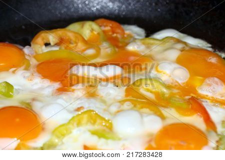 Preparation of morning scrambled eggs with fresh tomatoes and red pepper