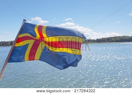 Flag from Aland (autonomous province of Finland) archipelago in the background