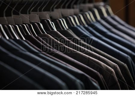 Row of men's suit jackets hanging in closet