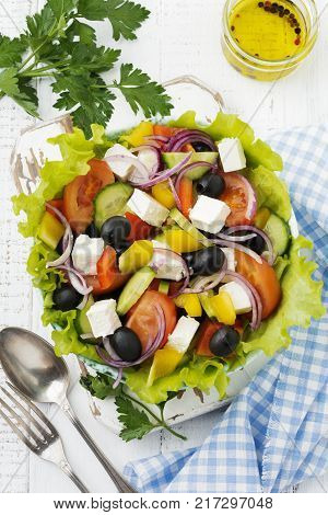 Greek salad in a ceramic plate on a white wooden background. Traditional Greek dish. Selective focus.Top view.