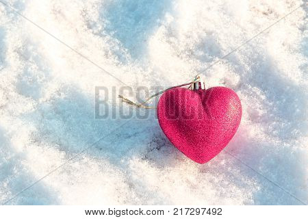 Red heart in the snow. The decoration on the Christmas tree. The spirit of Christmas. Christmas traditions. Winter mood and love. Heart on the snow. Valentine's day. Love and feelings