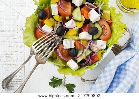 Greek salad in a ceramic plate on a white wooden background. Traditional Greek dish. Selective focus.Top view.