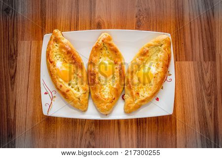 Khachapuri Ajarian on plate. Open pie with mozzarella and egg. Georgian cuisine.