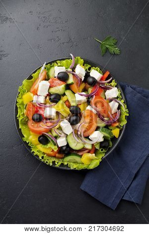 Greek salad in ceramic plate on gray concrete background. Traditional Greek dish. Selective focus.Top view.