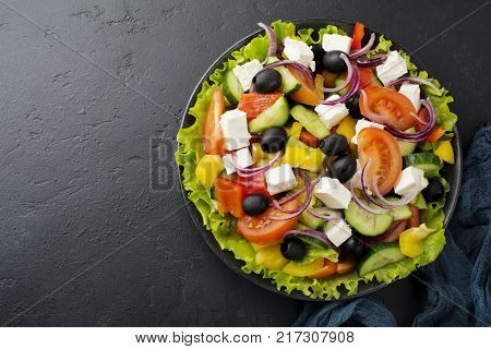 Greek salad in ceramic plate on gray concrete background. Traditional Greek dish. Selective focus.Top view.