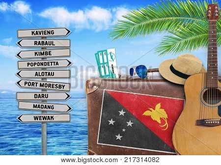 Concept of summer traveling with old suitcase and Papua New Guinea town sign