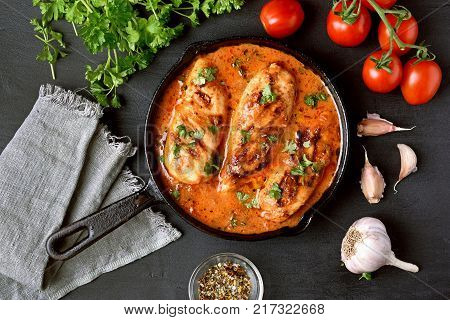 Cooked chicken breast with tomato sauce in frying pan. Top view flat lay