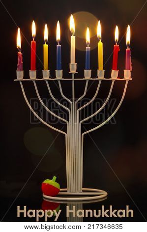 Happy Hanukkah jewish holiday. Menorah traditional candelabra with burning candles and Hanukkah Dreidel Sevivon against black background