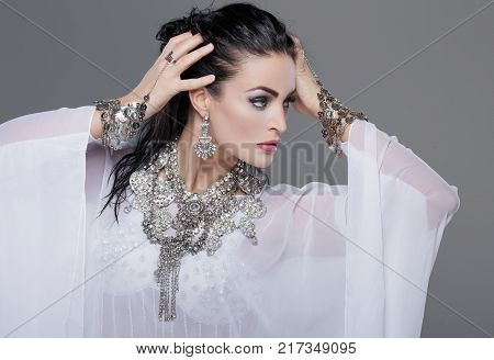 Sensual young belly dancer with gems posing portrait on grey backround