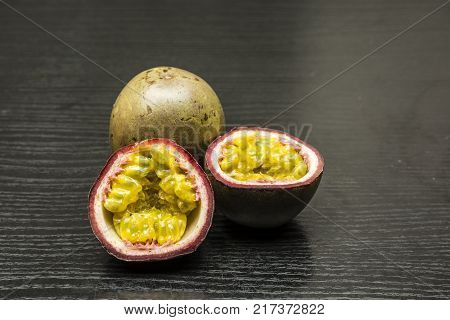 Split ripe fruit of Passiflora edulis on dark wood.