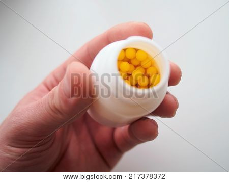 Yellow balls background. Vitamins in a hand on a white background. Against a background of pusyrek with vitamins.