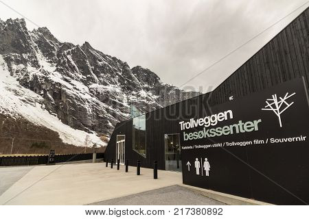 Rauma, Romsdalen in Norway - April, 19, 2017: Trollveggen visitor center with the peaks of Trollveggen in the backgorund. Snow. The Troll Wall, Trollveggen, is part of the mountain massif Trolltindene. It is the tallest vertical rock face in Europe,