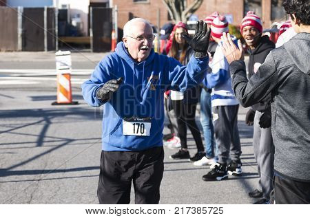 West Islip NY USA - 24 November 2017: A runner receives high fives from the school track team as he approaches the end of the annual Run Your Turkey Off 4K turkey trot.