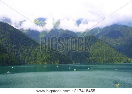 Beautiful panorama of natural mountain landscape with low clouds. Blue Lake Riza among mountains of the Caucasus, Abkhazia. Ritz Park