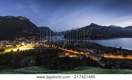 Night panorama of Lake Lucerne. Mountain range snow on the tops of the mountains. Axenstrasse. Lights in the houses and along the road.