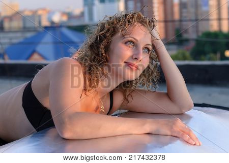 Young breautiful woman resting on roof at sunset