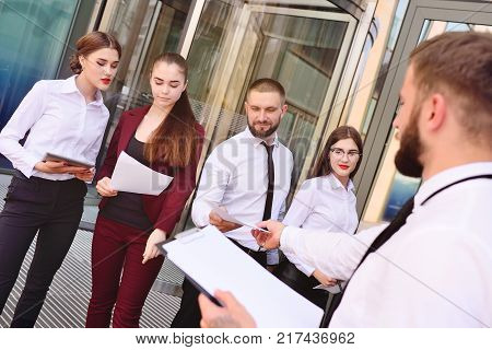 Director distributes subordinates task on the background of an office building