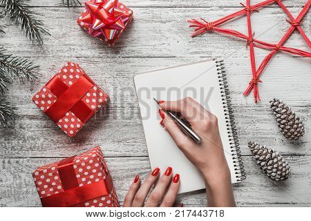 A modern background of a white background carnet background, and a young lady who writes a Christmas message with a white message board, a Christmas greeting card, a red star and a Christmas magic