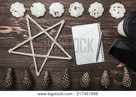 Brown wood background. Gold cones and sweet biscuits arranged diametrically opposed. Letter, phone, star and coffee, space for a greeting message. Top View.
